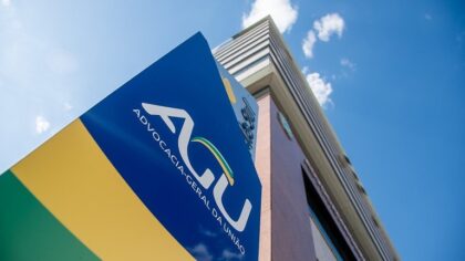 Chamada para Concurso AGU predio da instituição com placa inclinada com a sigla